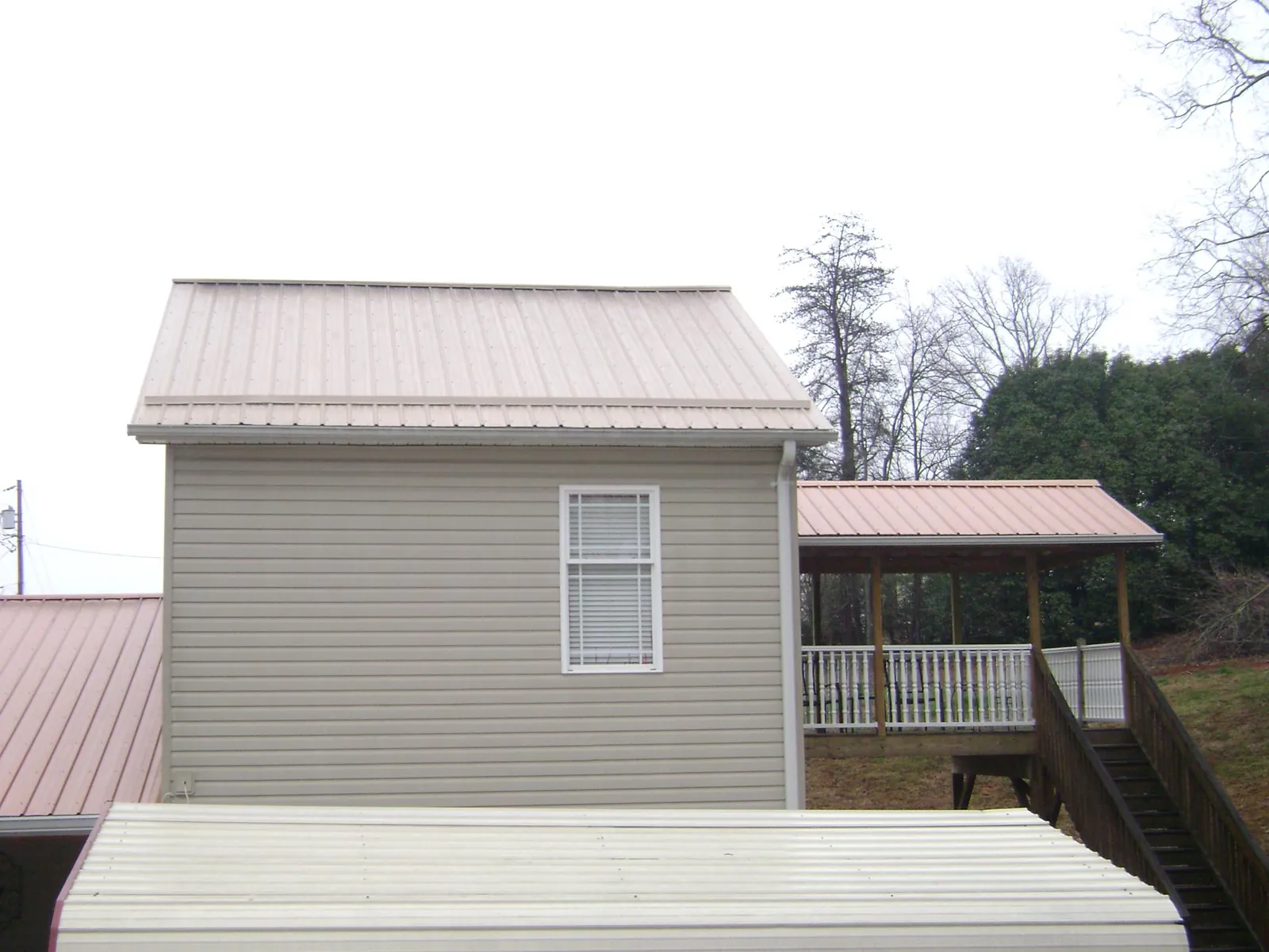 Tan metal roofs on a two story addition and attached porch, from a Roof Replacement job in Palmyra